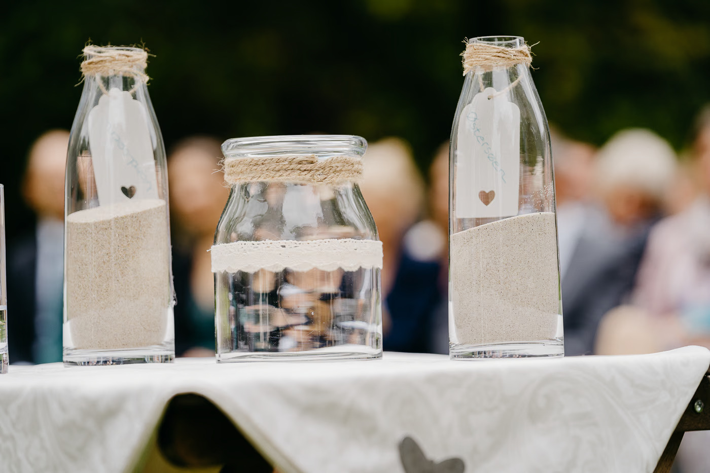 Freie Trauung Wolfenbüttel – Detailaufnahme Sanduhr-Zeremonie mit drei Glasflaschen gefüllt mit Sand und Jute-Dekoration, symbolische Hochzeitszeremonie Wolfenbüttel Kathrin Skorpel