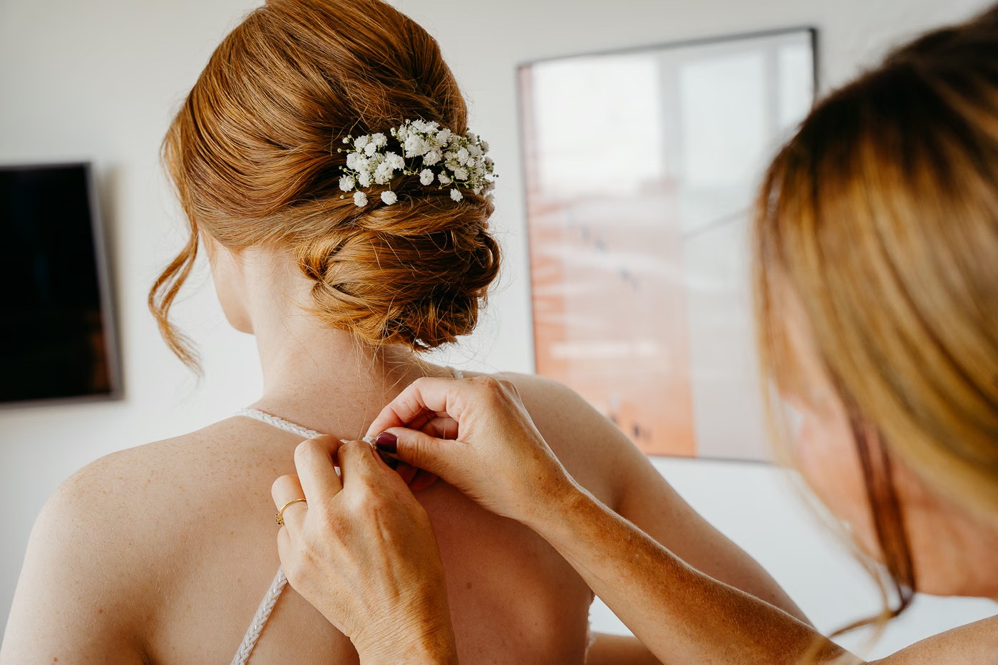 Getting Ready Hochzeit – Brautkleid wird von hinten zugeknöpft, elegante Hochzeitsfrisur mit Schleierkraut, Hochzeitsreportage Wolfsburg Kathrin Skorpel