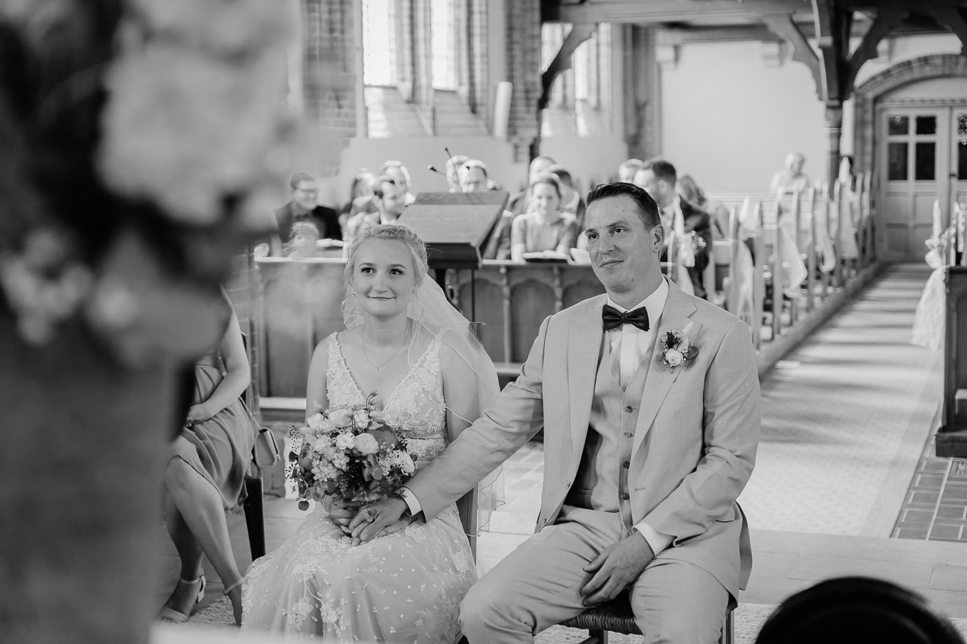 Kirchliche Trauung Braunschweig – Brautpaar sitzt nebeneinander in der Kirchenbank, Braut mit Schleier und Strauß, Gäste in Reihen dahinter, authentische Hochzeitsreportage Braunschweig Kathrin Skorpel