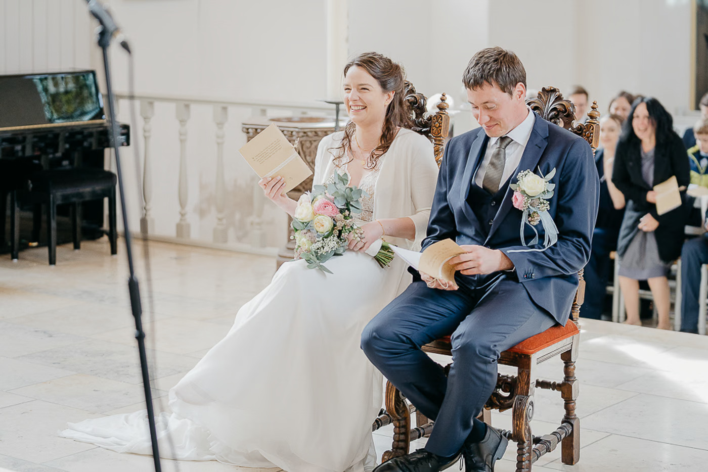 Kirchliche Trauung Gifhorn – Brautpaar hält gemeinsam das Hochzeitsheft und liest, Braut lacht dabei herzlich, natürlicher Moment bei der kirchlichen Trauung Gifhorn Kathrin Skorpel