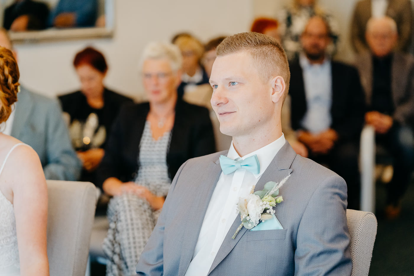 Standesamt Hochzeit Gifhorn – Bräutigam im grauen Anzug mit hellblauer Fliege und weißer Ansteckblume blickt zur Braut, ruhige Vorfreude während der Zeremonie, Hochzeitsfotografie Gifhorn Kathrin Skorpel
