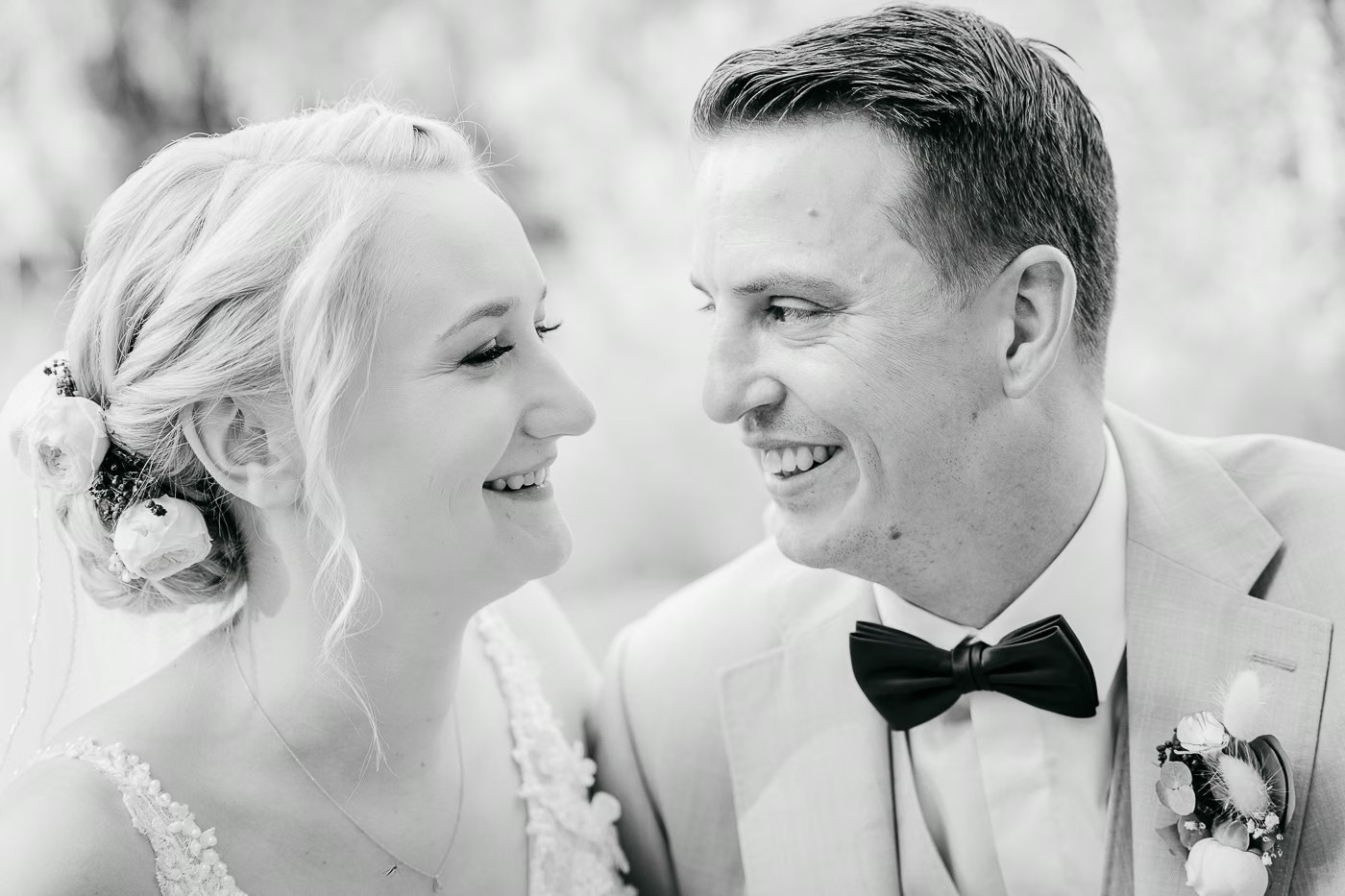 Schwarz-Weiß Hochzeitsfoto – strahlendes Brautpaar lacht sich an, zeitlose Hochzeitsfotografie